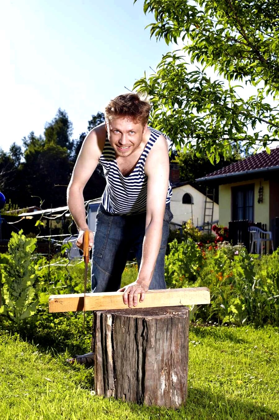 man cutting a piece of wood using a saw